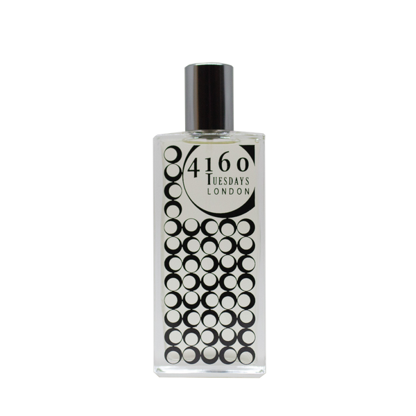 A clear glass perfume bottle with a silver cap. The bottle features a label with "4160Tuesdays" and a pattern of black circles, reminiscent of the delicate dance of damselflies over still waters, named "Butterlily Damselfly.
