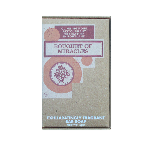 A beige box of bar soap labeled "Bouquet of Miracles Soap" by Imaginary Authors with shea butter, climbing rose, red currant, and springtime in Portland, Oregon. Net wt: 6 oz. Text includes "Exhilaratingly fragrant.
