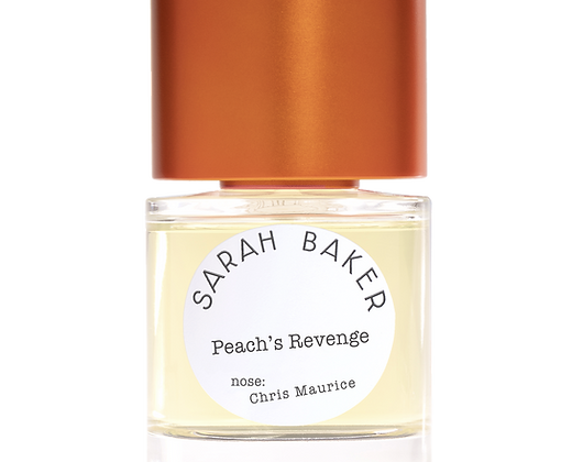 A clear bottle of perfume labeled "Peaches Revenge" by Sarah Baker, with a rose gold cap. The label also mentions "nose: Chris Maurice," featuring delightful hints of peach and exotic spices.