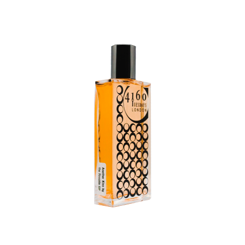 A rectangular bottle of 4160Tuesdays Another Kiss by the Fireside perfume with an orange liquid inside and a black cap. The label and circular patterns hint at its unique Perfume dialect, blending the essence of fireside fragrance with subtle undertones.