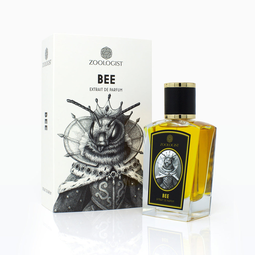 A boxed Zoologist Bee fragrance is shown. The gold-capped bottle, adorned with a bee illustration, exudes the rich aroma of honey and sits next to a box depicting a bee in royal attire.
