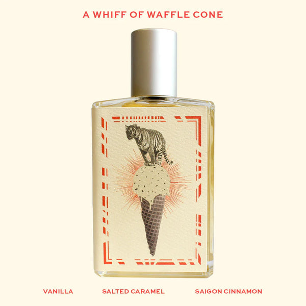 A perfume bottle with a label featuring a tiger standing on an ice cream cone, reminiscent of an old-fashioned ice cream shoppe. Text above reads "A Whiff of Wafflecone," and below lists "Vanilla," "Salted Caramel," and "Saigon Cinnamon." Imaginary Authors?