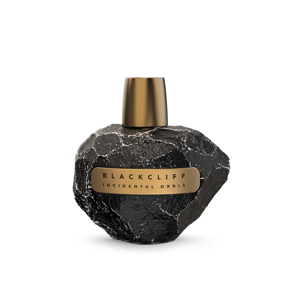 A black stone-textured perfume bottle with a gold cap and label, reading "Incidental Orris" by Blackcliff, captures the essence of forest bathing in its fragrance.