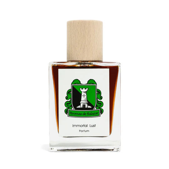 A glass bottle of perfume named "Immortal Lust" by the brand "Aromas de Salazar," featuring a wooden cap and adorned with a green and black emblem on the front, capturing the essence of lust with its jasmine sambac fragrance notes.