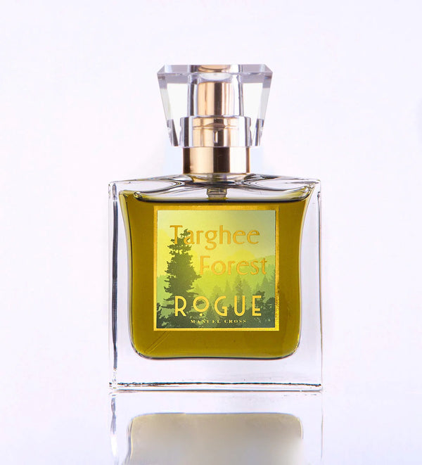 A clear glass bottle of Targhee Forest Rogue Perfumery Eau de Parfum with a gold cap, containing greenish-yellow liquid and a label featuring a woody forest design.