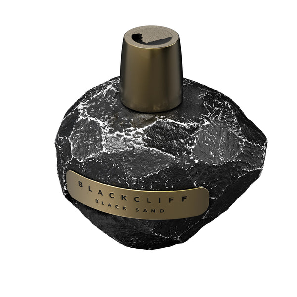 A perfume bottle designed to resemble a textured black rock, featuring a metallic cap and a label that reads "Blackcliff Black Sand," this Blackcliff Black Sand perfume tantalizes with woody musks and a smoky whiskey accord.