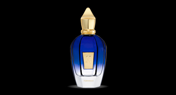 A blue glass Xerjoff Torino 21 bottle with a gold cap and gold label, displaying the text "TORINO21," captures the elegance of the Nitto ATP Tennis Finals in its sophisticated design.