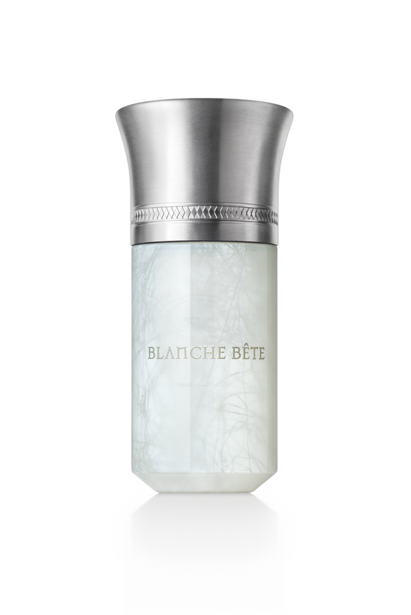 A cylindrical perfume bottle with a metallic cap and a frosted white body, labeled "Blanche Bete" by Liquides Imaginaires in gold lettering—like the essence of a mythical creature captured within.