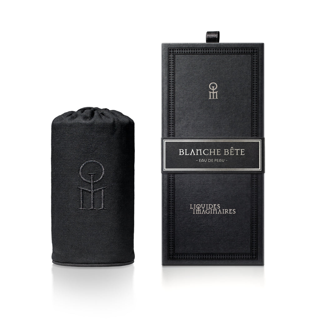 A black cylindrical pouch next to a black rectangular box labeled "Blanche Bete" by Liquides Imaginaires. The box features a minimalist design with subtle embossed details, evoking the elegance of a mythical creature.