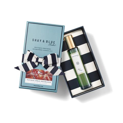 A Shay & Blue fragrance gift box with a bottle of their luxurious unisex perfume, Blood Oranges, inside. The box is open, revealing a striped lining and a decorative bow on the outside, all thoughtfully crafted with vegan materials.