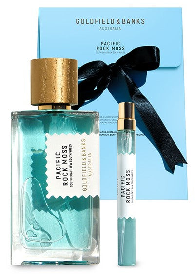 A set of "Pacific Rock Moss" perfume by Goldfield & Banks. This fresh perfume includes a large bottle, a travel size spray, and a blue box with a black ribbon – perfect for capturing the essence of beach life.
