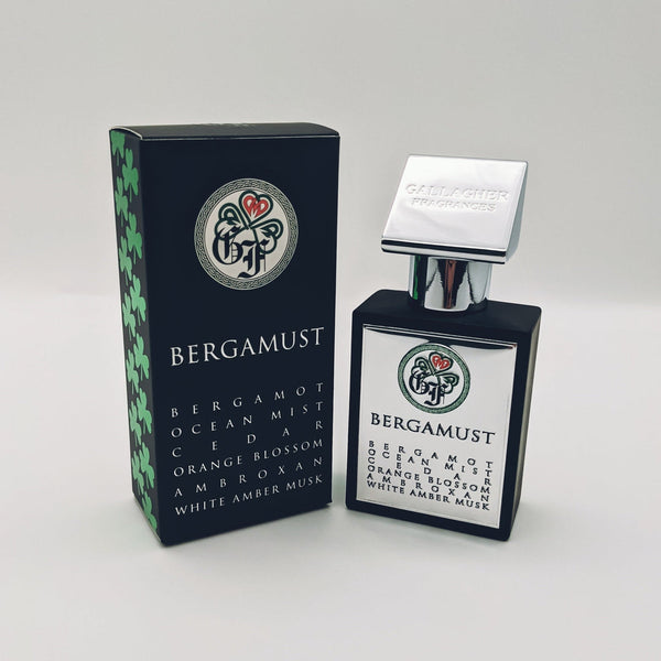 A bottle of Gallagher Fragrances' Bergamust fragrance stands next to its black box with green, white, and red design elements. The bottle's label lists its scent notes including bergamot, ocean mist, and cedar, perfectly capturing an exquisite aquatic fragrance.