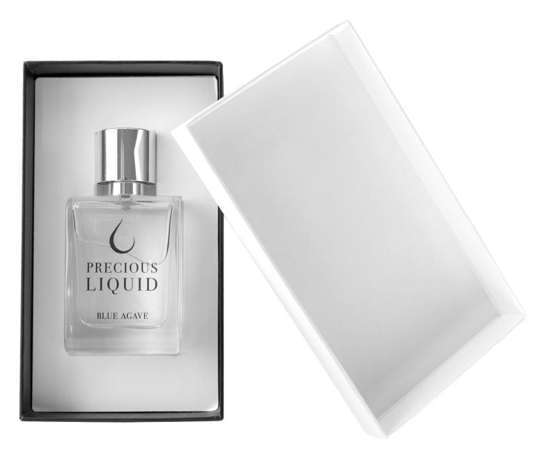 Glass bottle of "Blue Agave" perfume by Precious Liquid in a partially opened box with a white interior, featuring subtle hints of juniper berries within its luxurious woody fragrance.