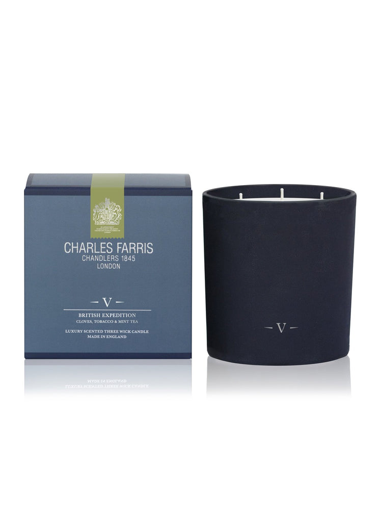 A British Expedition candle by Charles Farris in a black container, evocative of a Tobacco and Mint Tea Candle, is placed next to its blue and silver packaging box.