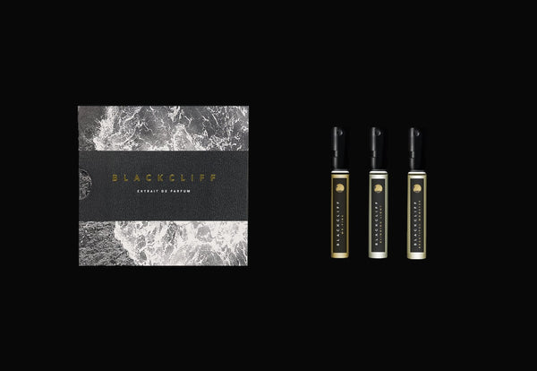 Box of Blackcliff BLACKCLIFF Discovery Set A on the left and three Blackcliff extrait de parfum bottles with black caps on the right, against a black background.