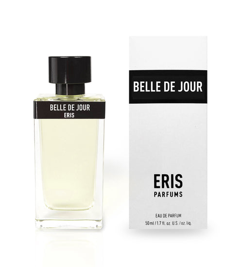 A bottle of Belle de Jour by Eris Parfums rests next to its white and black packaging box. The bottle contains clear liquid with a black cap and label. The elegant fragrance, highlighted by notes of orange flower and jasmine, is reflected in both the sleek design and thorough branding on the box.