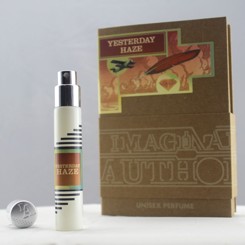 A bottle of Yesterday Haze unisex perfume by Imaginary Authors stands next to its box packaging, which features colorful, abstract artwork. Renowned perfumer Lenora Blumberg crafted this seductive scent to captivate and enchant.