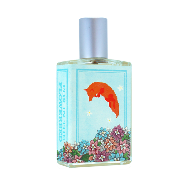 A perfume bottle with a blue label showcasing an illustration of a fox above a flower bed, titled "Fox in the Flowerbed." Evoking Alpine fairy tales, the floral fragrance of the pale yellow liquid inside is reminiscent of Chunhua Luli. This enchanting scent is brought to you by Imaginary Authors.