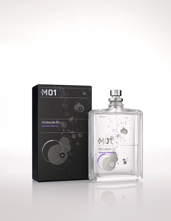 Image of Escentric Molecules' Molecule 01 fragrance bottle and its packaging. The transparent bottle with minimalistic design elements holds the signature Iso E Super scent, while the sleek black packaging features similar graphics.