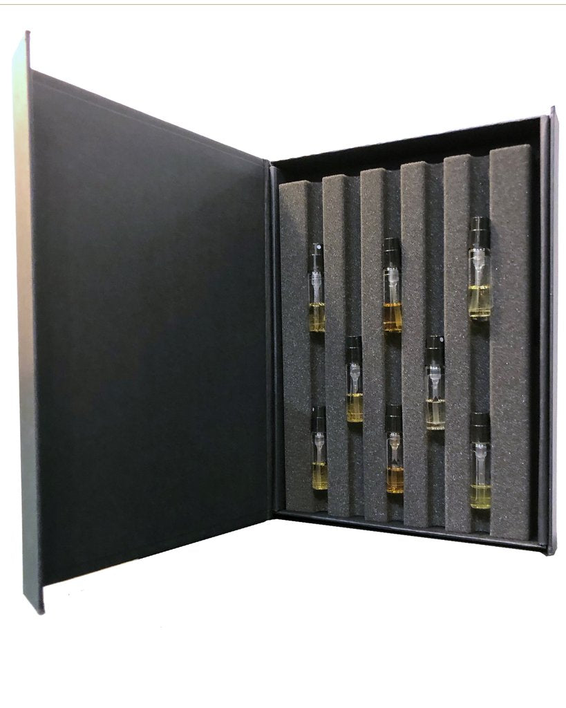 Open black box displaying nine small glass vials of Baruti Parfums Discovery Set by Baruti, each containing unique fragrances, neatly arranged in foam padding.