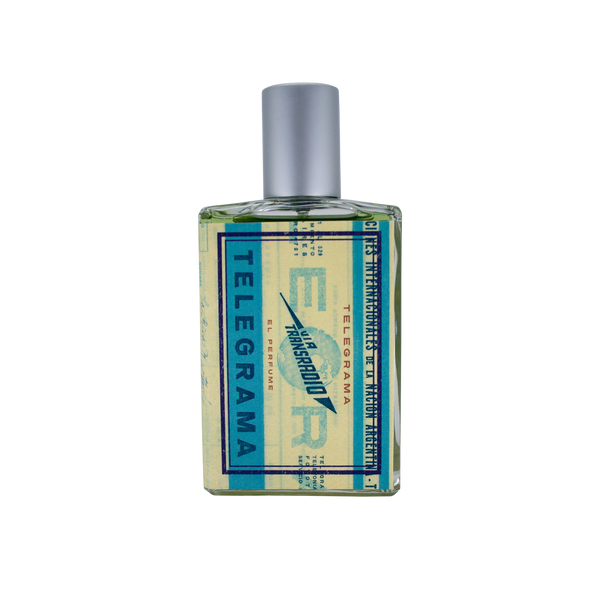 A square glass bottle of perfume with a blue and yellow label that reads "Telegrama" and "Imaginary Authors," exudes a vintage first-class experience. The bottle, topped with a silver cap, contains a plush scent that leaves an impression as timeless as Lavender Absolute.