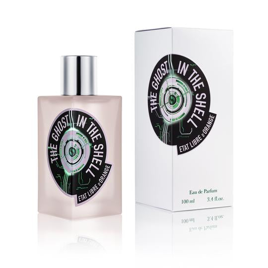 A bottle of "The Ghost In The Shell" perfume by État Libre d'Orange stands beside its matching box. The bottle, reminiscent of a Dan Simmons novel cover, is rectangular with a silver cap and has a black and green circular label.