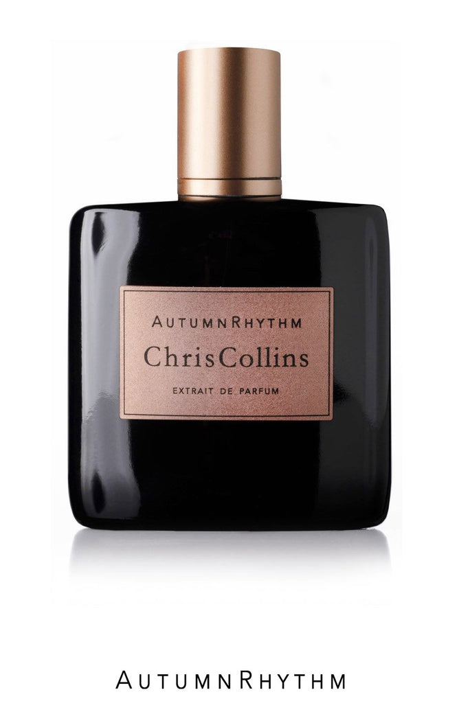 A black bottle of "Autumn Rhythm" Extrait de Parfum by Chris Collins, featuring a gold label and cap, is displayed against a white background. The rich fragrance boasts a leather note, perfectly capturing the essence of autumn. The name "Autumn Rhythm" is elegantly written below the bottle.