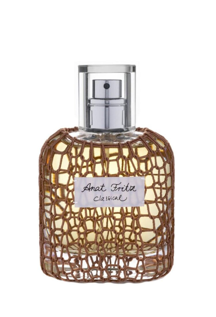 A bottle of Classical 2020 Ltd. Edition labeled "Anat Fritz," encased in a net-like, woven cover, with hints of lavender and cedar wood.