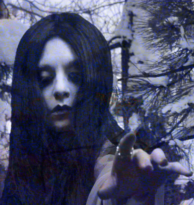 A person with long dark hair extends their hand towards the camera in an outdoor snowy scene, evoking the ethereal presence of Ikiryo's Yukion'na amid a serene Japanese forest.