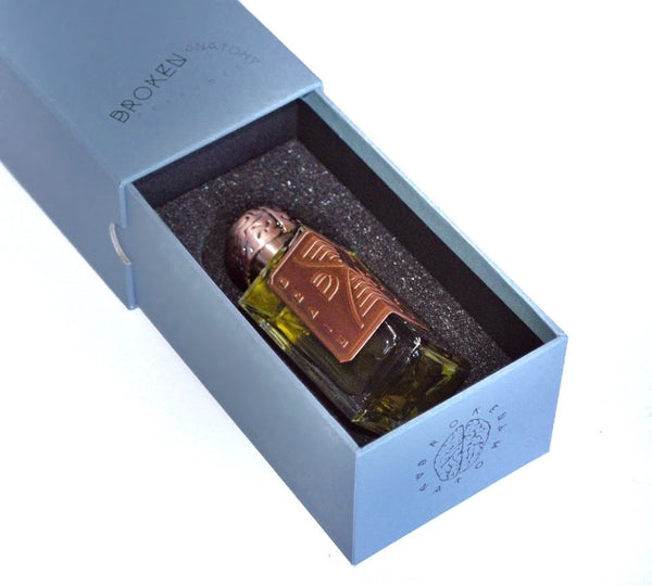 A bottle of Brain Dance with a brown cap and label sits in a blue box with foam padding inside, labeled with "Broken Anatomy" and logo.