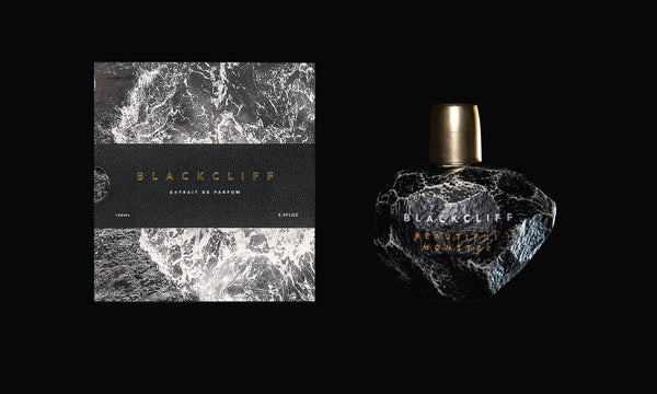 An image displays a cologne set, featuring a box and a bottle. The box has a black and white marble-like design with the text "Blackcliff" and "EXTRAIT DE PARFUM". The bottle, with its black, rock-like appearance, hints at undertones of Beautiful Monster by Blackcliff, enriched by Atlas Cedarwood and Geranium Heart.