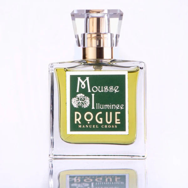 Square glass perfume bottle with a gold and crystal cap. The label on the front reads "Mousse Illuminee ROGUE PERUMERY" in white text on a green background. The liquid inside is pale yellow, exuding the essence of Treemoss and Green Cypress for a fresh, natural scent.