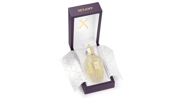 A bottle of Xerjoff's Sketchbook P. 33 perfume from the exclusive Sketchbook Collection in a partially opened purple box, with white and gold tissue paper. The bottle is clear with a gold cap and features a gold label on the front, exuding luxury with its floral and fruity notes.