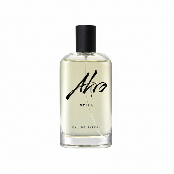 A clear glass bottle of Akro's SMILE Eau de Parfum, a happiness fragrance featuring a black cap and black text on the front.