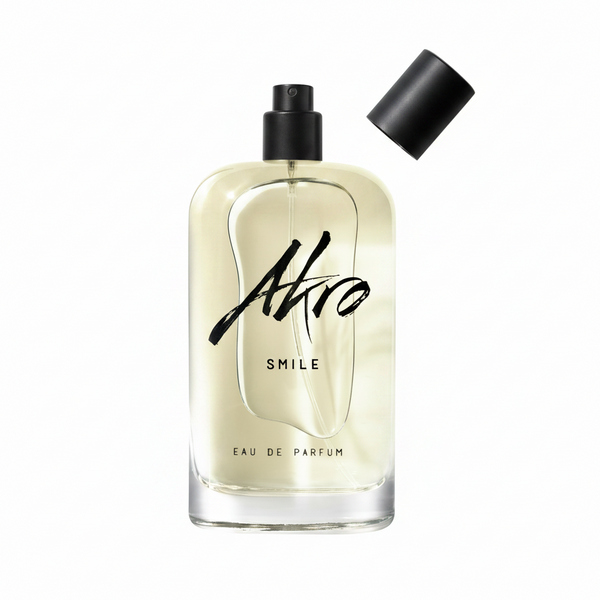 A transparent bottle of Akro's SMILE Eau de Parfum, a unisex fragrance, with a black spray cap removed and placed to the side.