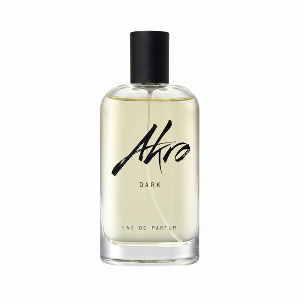 A clear glass perfume bottle with a black cap, labeled "Akro DARK," containing a light yellow liquid that exudes a mature sensuality and an addictive chocolate fragrance.