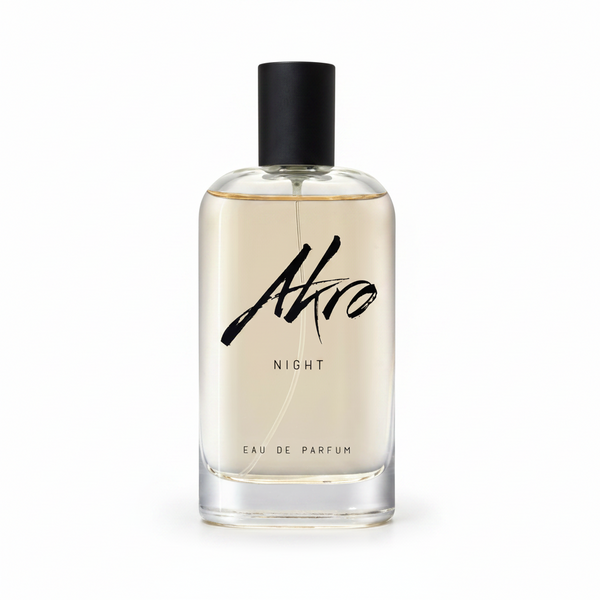 A clear bottle with a black cap labeled "Akro NIGHT Eau De Parfum." The light yellow liquid inside features musky notes.