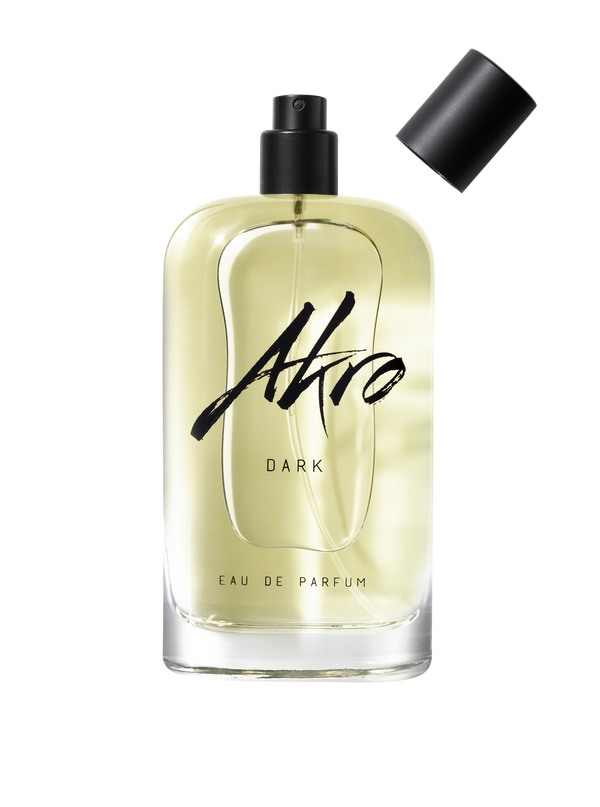 A clear glass bottle of Akro DARK Eau de Parfum with a black spray top and detachable cap, exuding mature sensuality with its addictive chocolate fragrance.