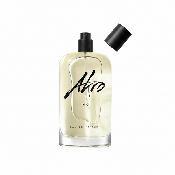 A clear glass bottle of INK by Akro Eau de Parfum featuring a black spray nozzle, with its detached black cap placed to the side, capturing the essence of its unique tattoo fragrance.