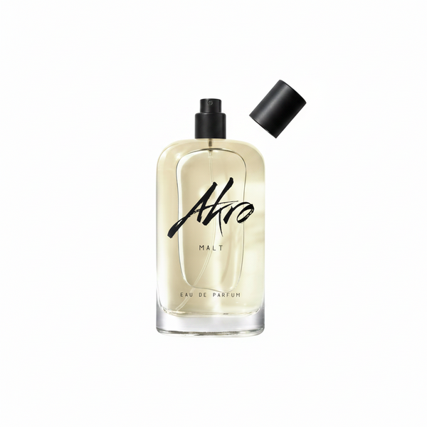 A clear glass bottle of MALT Eau de Parfum by Akro, exuding a rich whisky fragrance with a hint of smoky aroma, stands with its black spray cap removed and placed nearby.