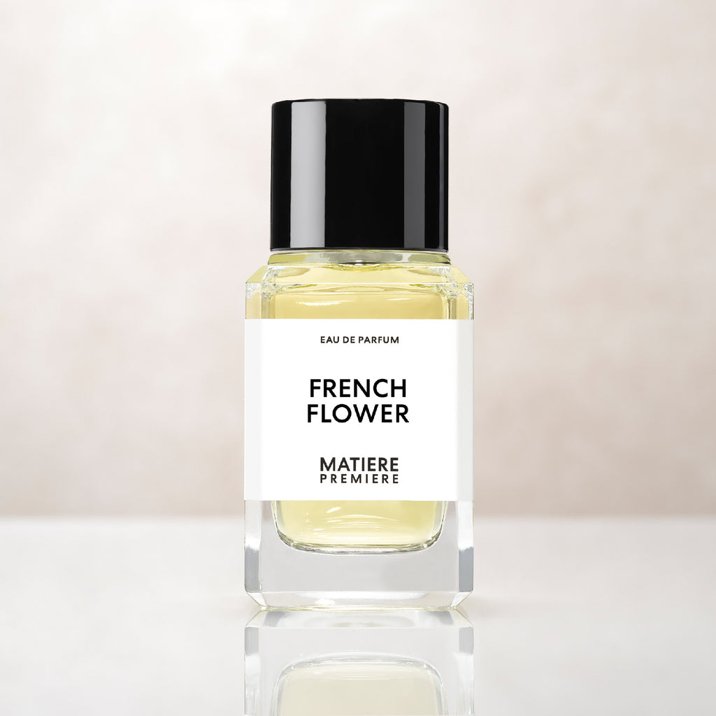 A clear glass bottle of French Flower by Matiere Premiere with a black cap, enhanced by the elegance of Tuberose, placed against a light, neutral background.