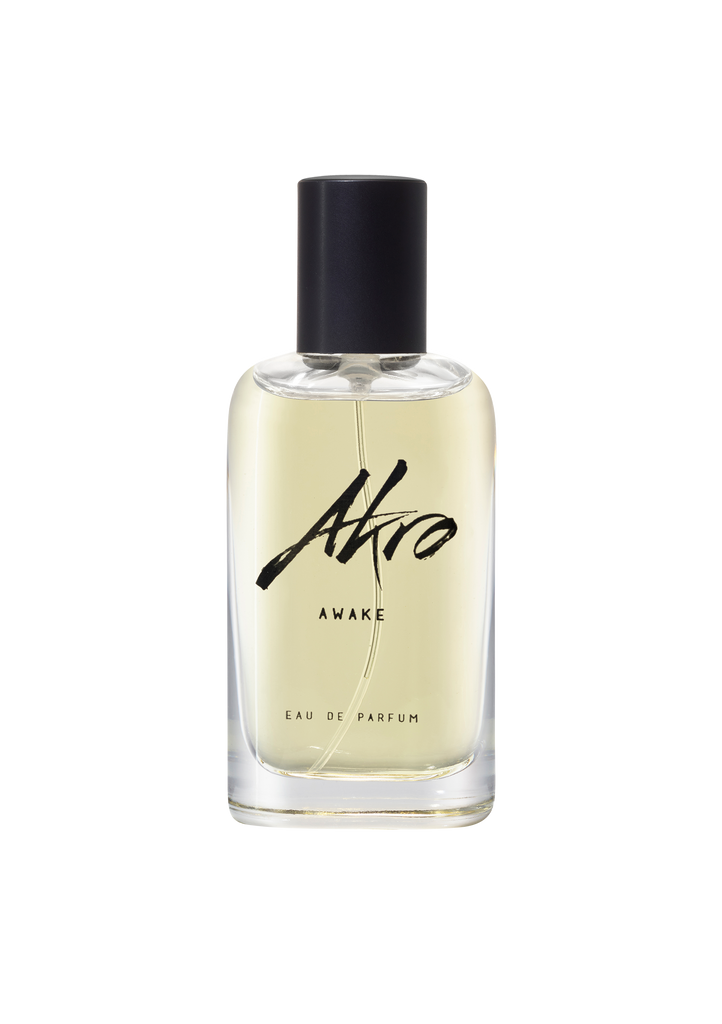 A clear bottle of Akro AWAKE Eau de Parfum with a black cap. The light yellow unisex perfume boasts a captivating coffee fragrance. The bottle's label reads "Akro" with "AWAKE" written underneath.