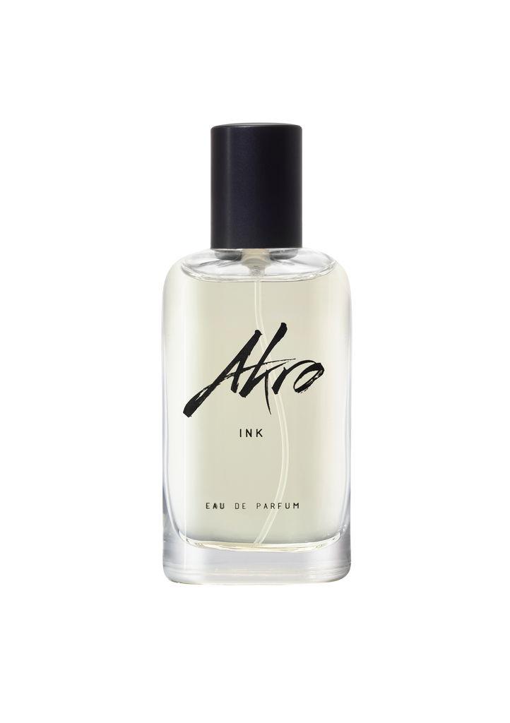 A clear glass bottle of Akro INK Eau de Parfum with a black cap and minimalist label, exuding a tattoo fragrance that captures the essence of black ink.