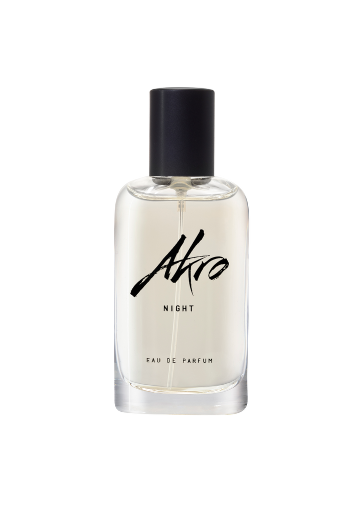 Clear glass bottle of Akro NIGHT Eau de Parfum with a black cap and black text on the label, exuding musky notes and a hint of Bulgarian rose.