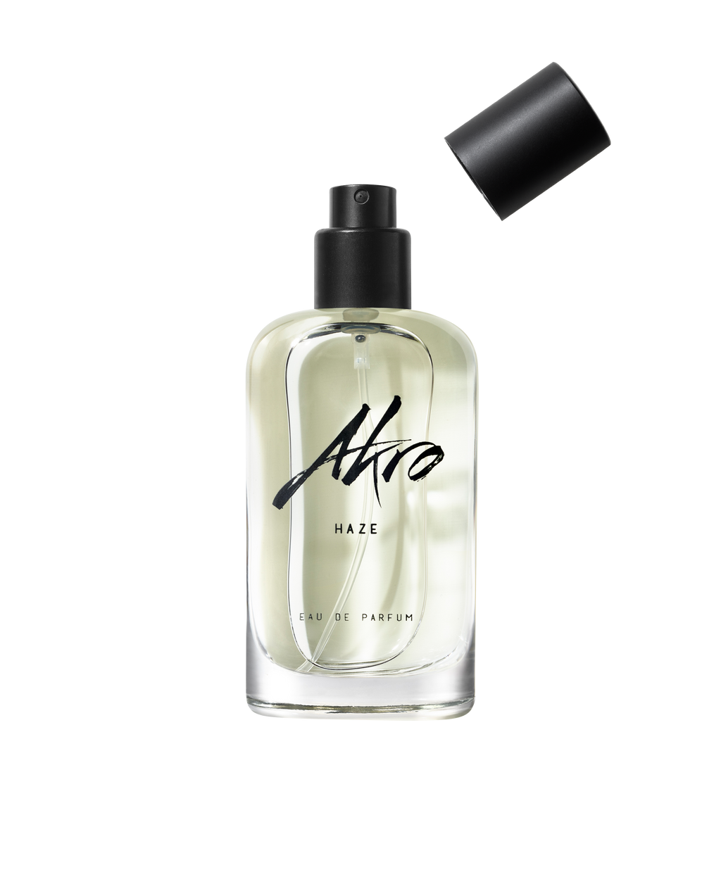 Clear glass bottle of Akro HAZE Eau de Parfum with a black cap removed and positioned above the bottle, exuding a smoky scent.