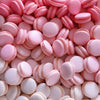 Pile of pink macaron cookies with smooth shells and pastel filling