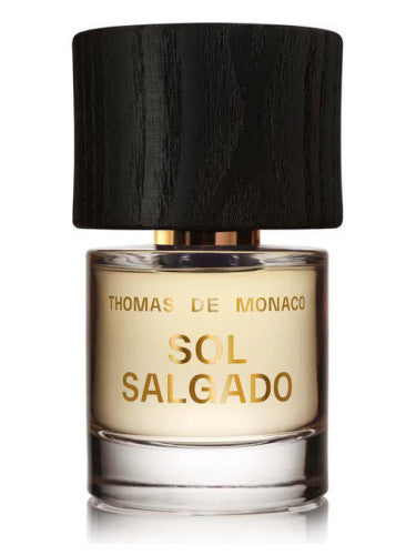A bottle of Thomas De Monaco's Sol Salgado Extrait de Parfum, featuring a wooden black cap and gold lettering on the glass, capturing the essence of an endless summer.