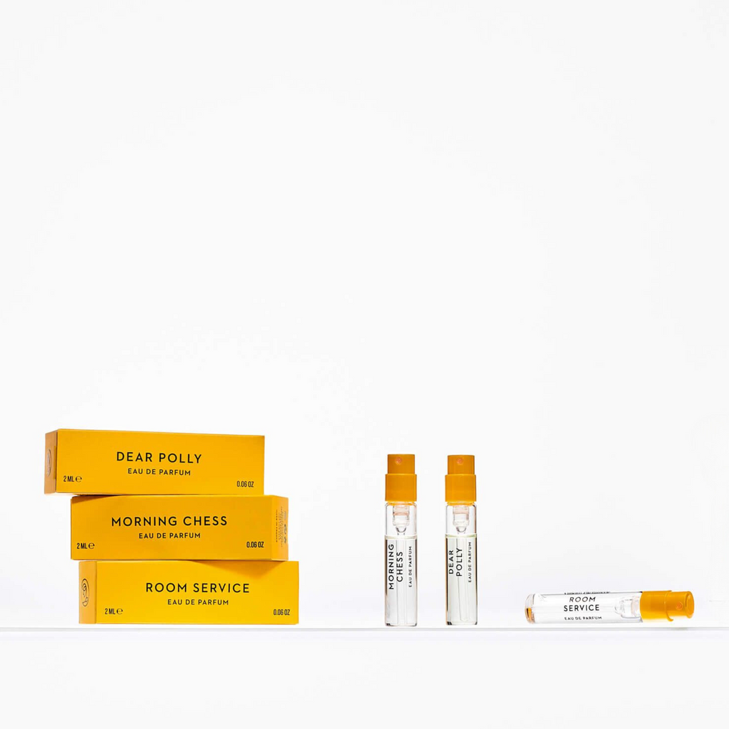 A photo of the Vilhelm Parfumerie Vilhelm 6x2 ml Discovery Set showcases these sought-after scents, with three corresponding small perfume sample bottles placed beside them on a white background.