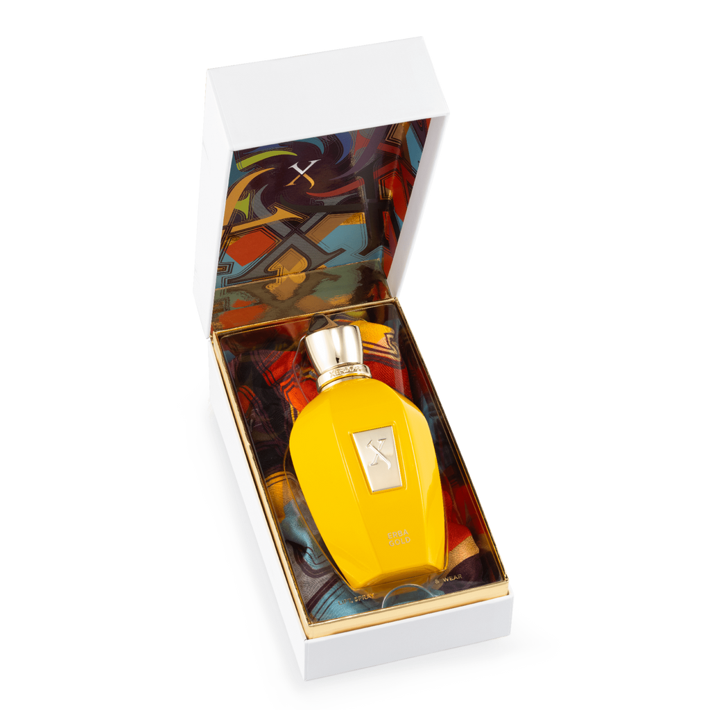 A yellow perfume bottle with a gold cap, featuring Xerjoff's Erba Gold's citrusy top notes, rests elegantly in an open white box with a colorful interior design.