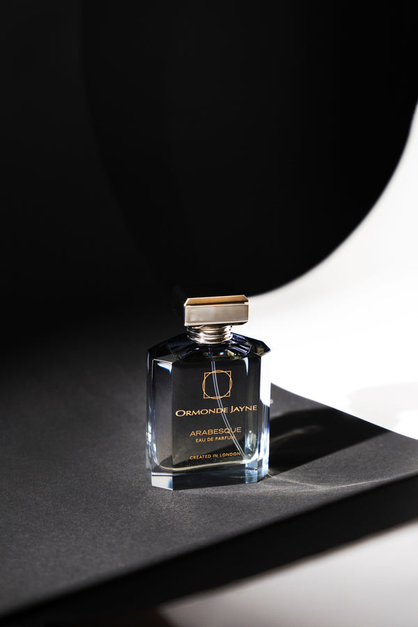 A bottle of Ormonde Jayne Arabesque, featuring rich notes of rose and jasmine, is displayed on a dark, minimalist background.